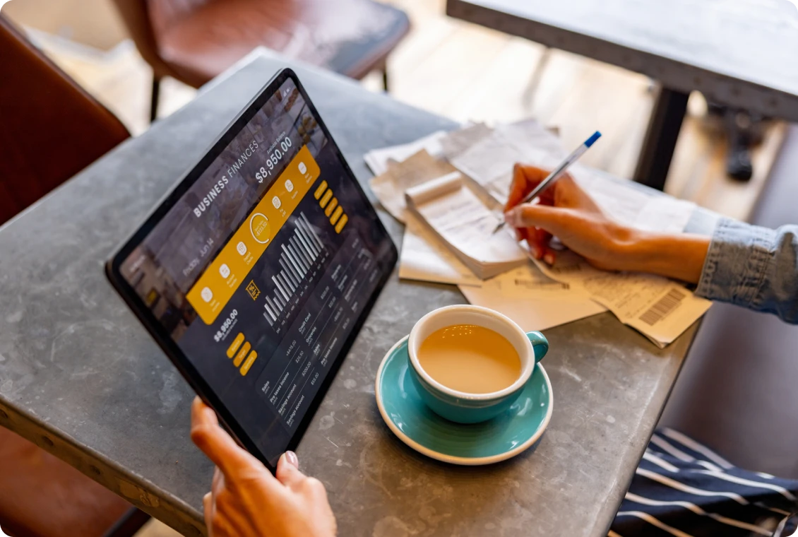Person writing near coffee and tablet